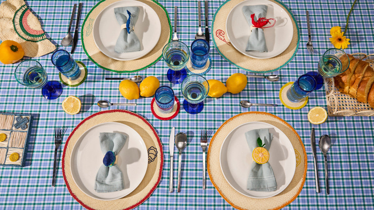 Four place settings with handwoven placemats and plates on a blue checked tablecloth, showing placemat proportions