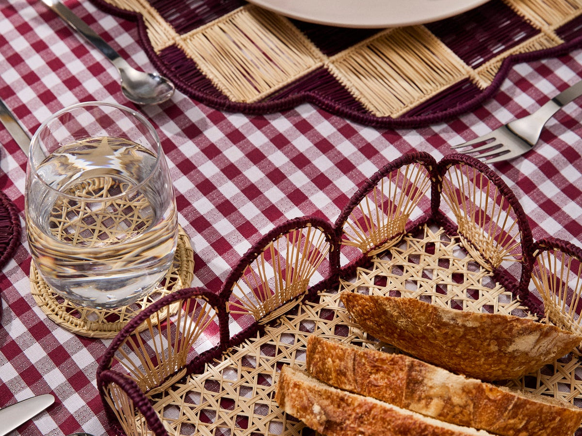 Handwoven bread basket and placemat on a burgundy gingham tablecloth