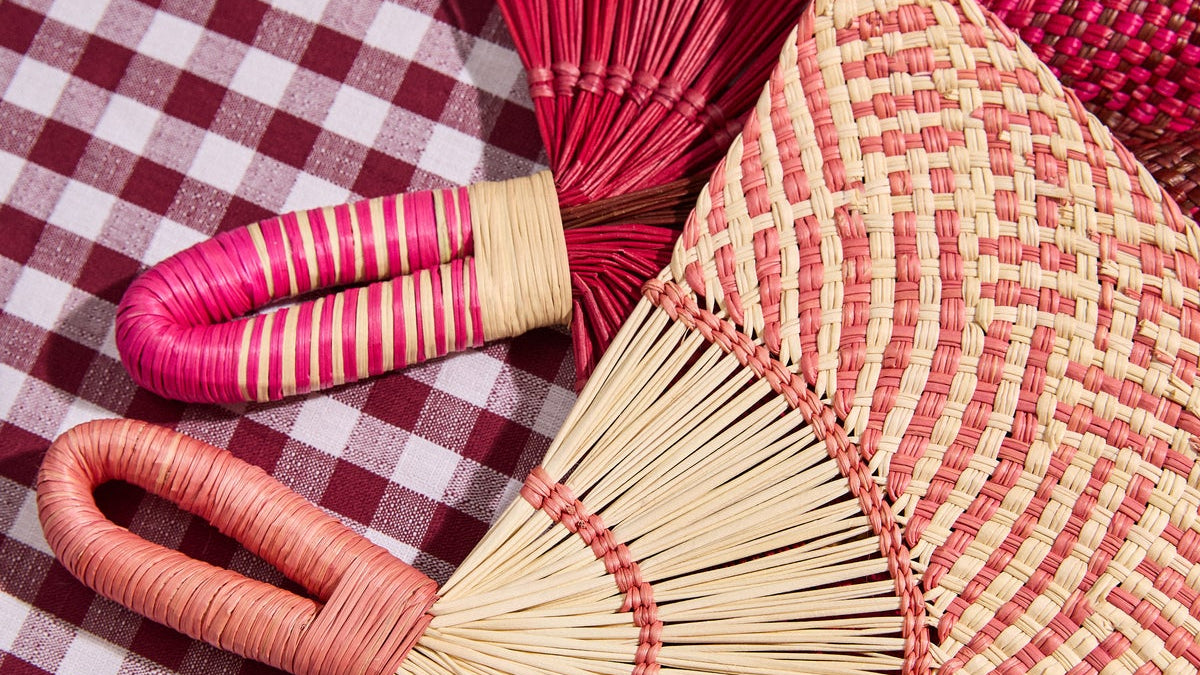 Handwoven fans and a woven placemat on a burgundy gingham tablecloth