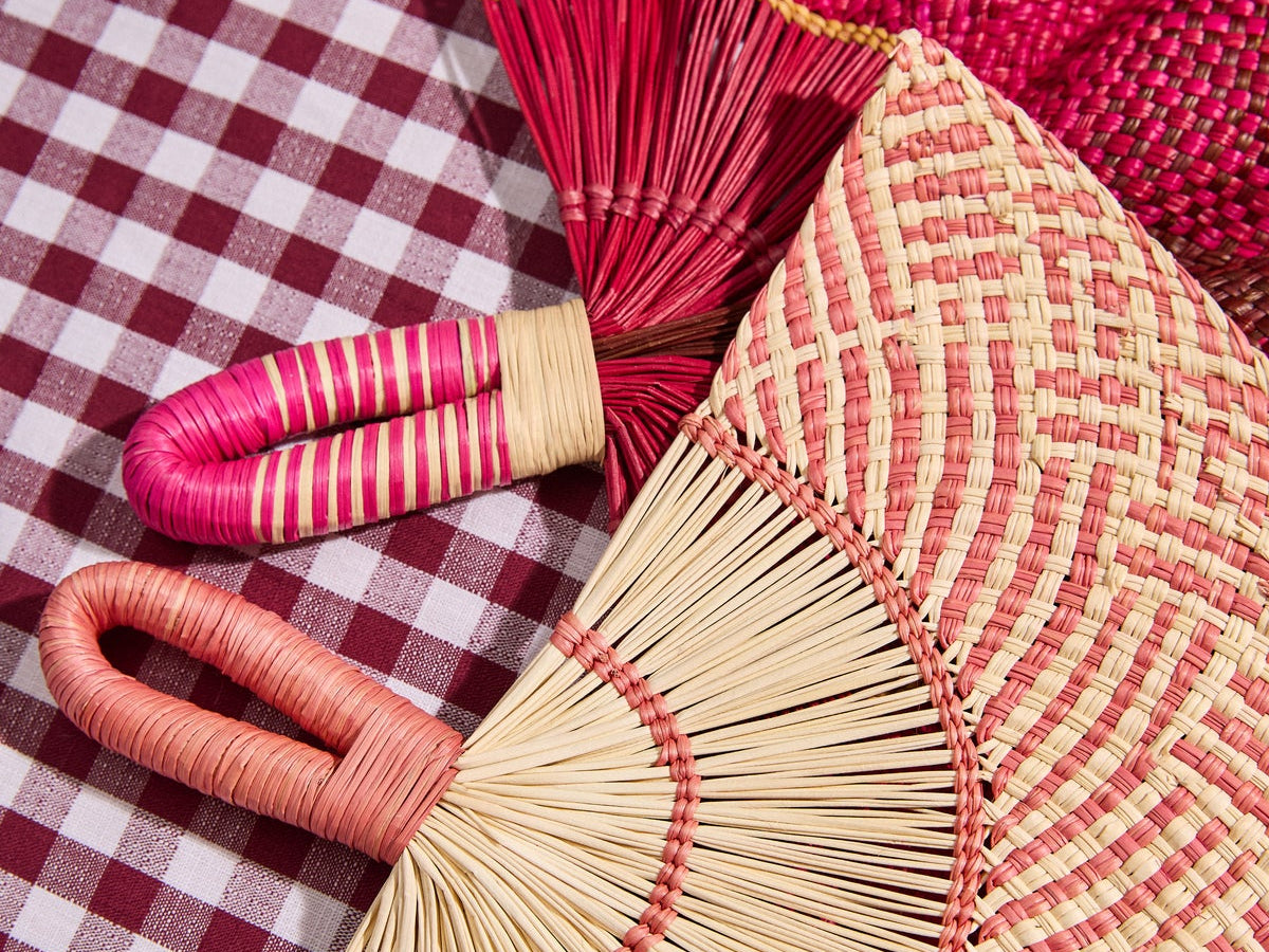Handwoven fans and a woven placemat on a burgundy gingham tablecloth