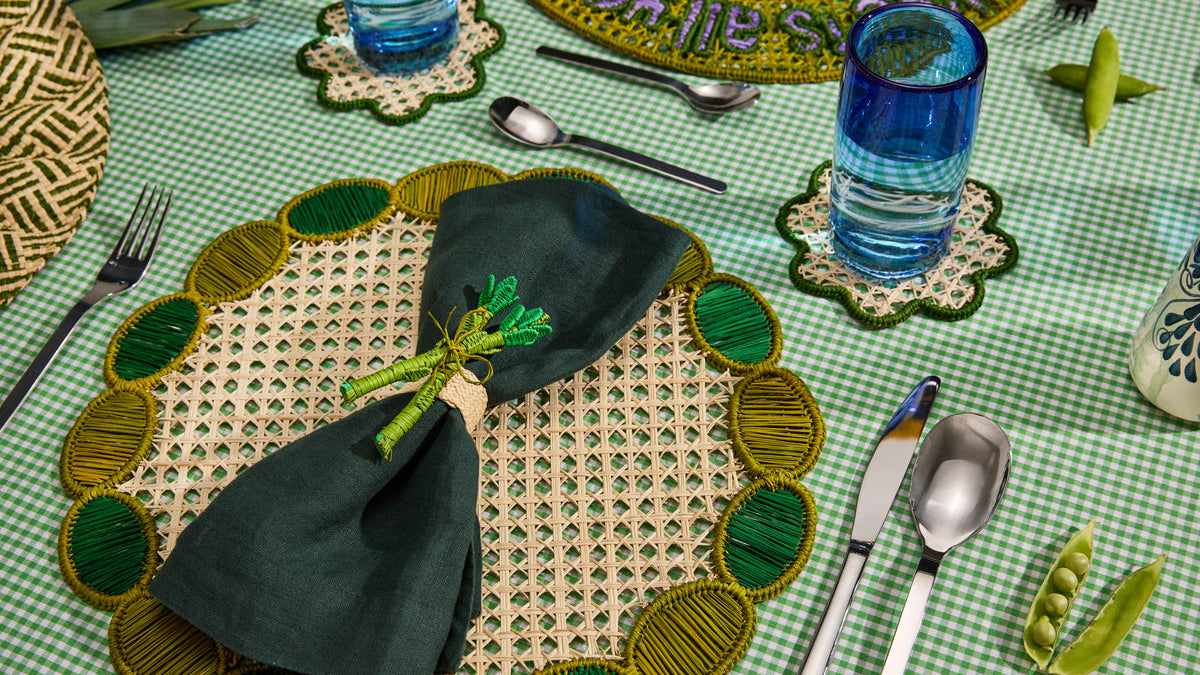 Green handwoven placemat with a dark napkin and a pea-shaped napkin ring