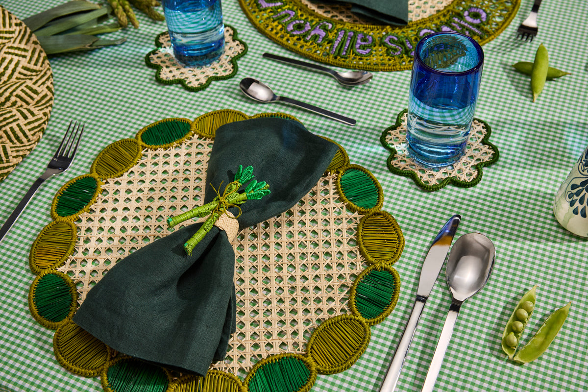 Green handwoven placemat with a dark napkin and a pea-shaped napkin ring