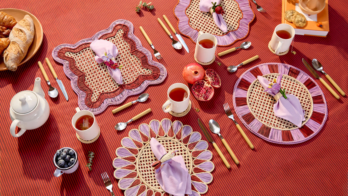 Autumn table with handwoven placemats, napkin rings and pomegranates on a terracotta tablecloth, set by Coro Cora