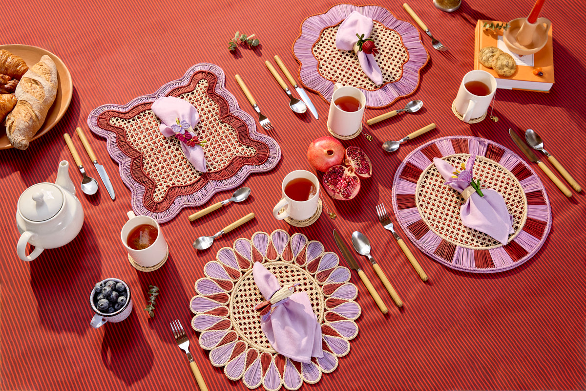 Autumn table with handwoven placemats, napkin rings and pomegranates on a terracotta tablecloth, set by Coro Cora